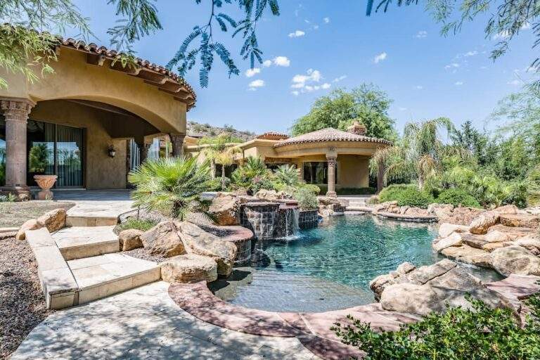 Luxury backyard swimming pool with a natural stone waterfall, rock grotto, and flagstone patio.